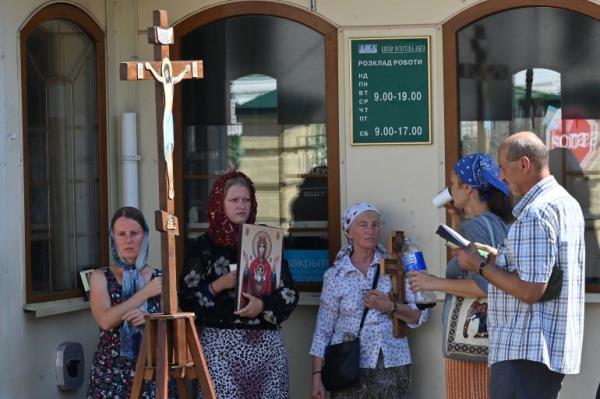 A handful of UOC followers pray outside the Kyiv Pechersk Lavra. They are holding icons and prayer books.