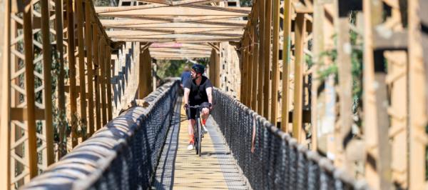 A cyclist is riding across a bridge towards the camera